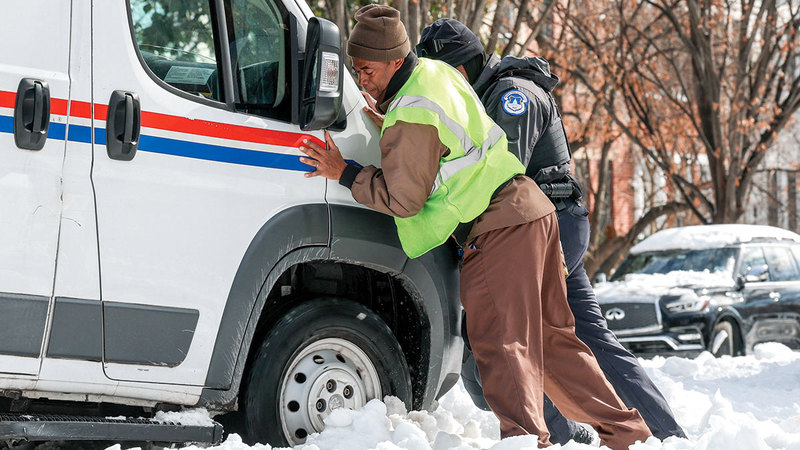 أشخاص يساعدون في دفع شاحنة تابعة
للخدمة البريدية الأميركية. رويترز