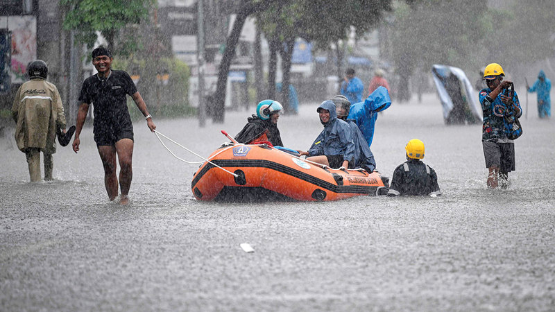 أحد السكان المحليين ينقل نزلاء فندق باستخدام قارب مطاطي. أ.ف.ب