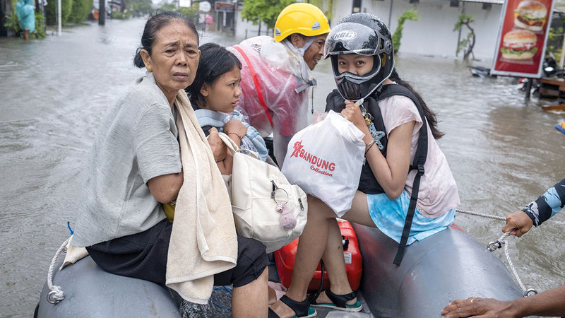رجال إنقاذ يستخدمون قارباً مطاطياً لعبور مياه الفيضانات في كوتا. إي.بي.إيه