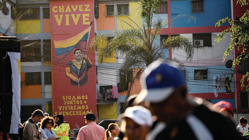 متظاهرون أمام جدارية لتشافيز تحمل عبارة
&laquo;لنتحد.. سنعيش وسننتصر &raquo;. رويترز