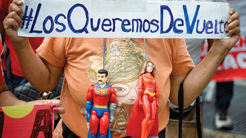 امرأة تحمل لافتة كتب عليها &laquo;نريد عودتهما &raquo;
إلى جانب مجسمين لمادورو وزوجته. رويترز