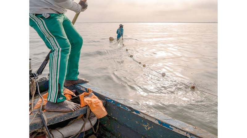 أحد الصيادين ينشر شبكته لصيد السمك على شاطئ جزيرة &laquo;بوباك&raquo;. من المصدر