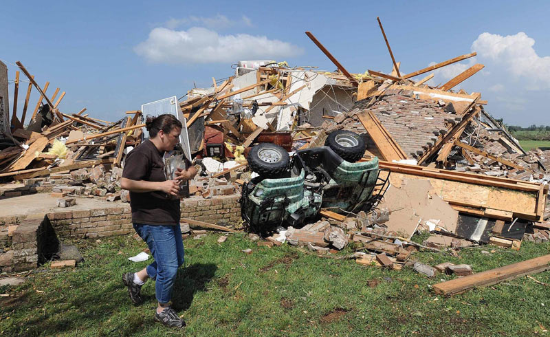 سيدة تحاول إنقاذ ما يمكن إنقاذه من أمام منزلها الذي دمره الإعصار.  د ب أ