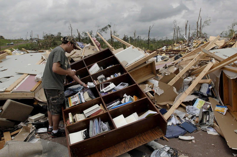 أما هذا الرجل فيحاول جمع كتبه القيمة التي نجت من الإعصار. د ب أ