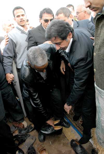 صورة أرشيفية تظهر أحد مرافقي الأمين السابق للتنظيم في الحزب الوطني الحاكم في مصر،أحمدعز، يساعده على انتعال الحذاء، بعد خروجه من احد المساجد في القاهرة-إنترنت