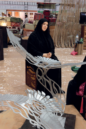 القبيسي مع أحد تصاميمها المشاركة . من المصدر