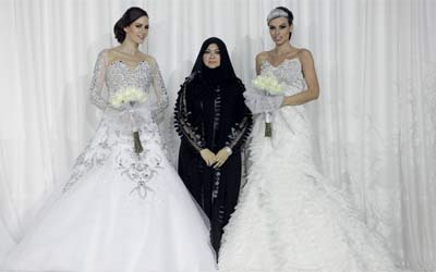 منى المنصوري مع عارضتين ترتديان تصميميها لفستان العروس.	تصوير: إريك أرازاس