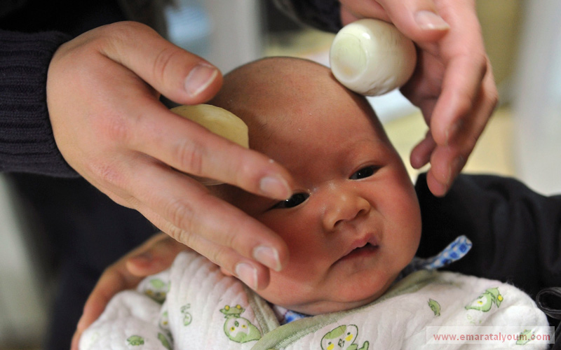 أب يعمل على تدليك رأس ابنه بـ"البيض" بعد أن حلق رأسه في صالون حلاقة في منطقة هيفي بمحافظة آنهوي، احتفالا بقدوم اليوم الثالث والعشرين من شهر فبراير. رويترز
