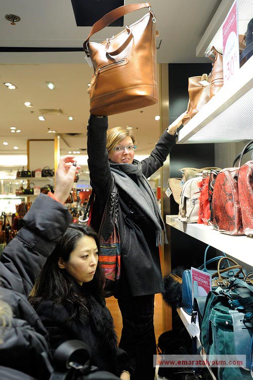 إمرأة من المتسوقين تأخذ على عاتقها مساعدة آخريات في الحصول على حقائب في العاصمة الفرنسية باريس. إي بي أيه