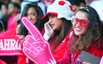 مشجعة بحرينية تتسلح بأرضها وتعوّل على الأحمر للحفاظ على الابتسامة.   	   أ.ف.ب