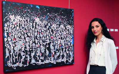 الفنانة لينا عقيلي مع إحدى لوحاتها.