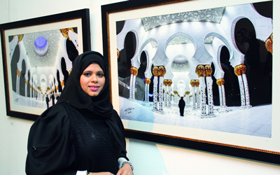 الفنانة علا اللوز مع إحدى لوحاتها المشاركة في معرض المرأة في الفن.