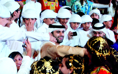 منصور بن محمد متوسطاً عدداً من الأطفال المشاركين في العرض الغنائي.