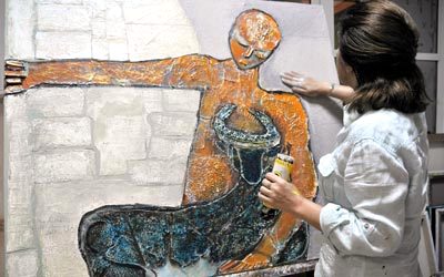الفنانة سلمى المري في مرسمها خلال مشاركتها في ملتقى دبي التشكيلي. من المصدر