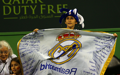 طفل صغير يحمل شعار الريال خلال مباراة في بطولة الدوحة للتنس. رويترز