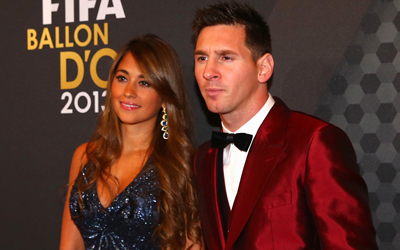 ميسي ببدلته الحمراء مع زوجته أنتونيلا. غيتي