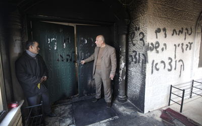 فلسطينيان أمام مدخل مسجد علي بن أبي طالب في بلدة ديراستيا الذي أحرقه مستوطنون. أ.ف.ب