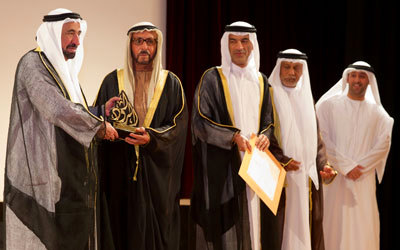 سلطان القاسمي مكرِّماً الشاعر حمد بن سوقات. من المصدر