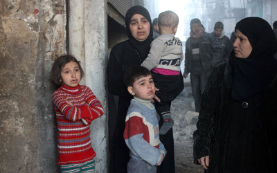 امرأة وأطفالها يقفون مذعورين عقب إلقاء القوات النظامية برميلاً متفجراً على أحد أحياء حلب. أ.ف.ب