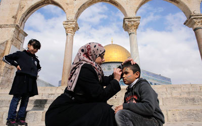 معلمة فلسطينية ترسم على وجه تلميذ خلال زيارة مدرسية إلى «الأقصى».   رويترز
