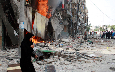 امرأة تهرب بعيداً عن مبنى يحترق عقب قصف نفذته قوات النظام على حي بستان القصر في حلب. رويترز