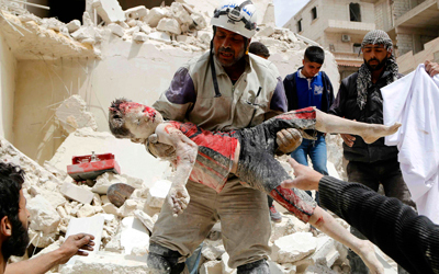 مسعف يحمل جثة طفل قتل بإلقاء القوات السورية برميلاً متفجراً على حي كرم البيك في حلب. رويترز