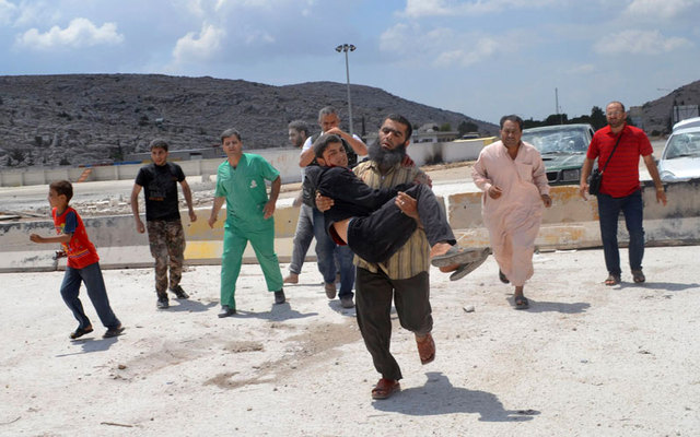رجل يحمل جريحاً أصيب في قصف القوات السورية على منطقة باب الهوى الحدودية مع تركيا.  رويترز