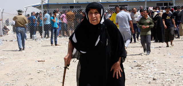 عجوز عراقية تتوكأ على عصاها أثناء هروبها من القتال.  رويترز