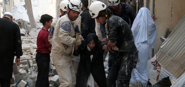 رجلا إنقاذ يساعدان مسنّة في أعقاب انفجار برميل متفجر على حي الشعّار بحلب.  رويترز