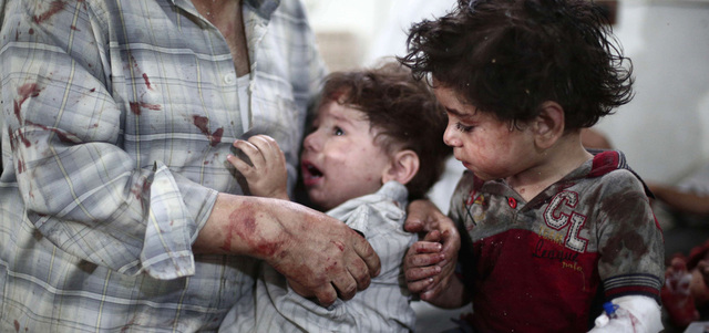 طفلان بجانب والدهما في مستشفى ميداني عقب إصابتهما بانفجار سيارة مفخّخة في دوما. أ.ف.ب