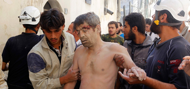 عناصر من الدفاع المدني يساعدون رجلاً أصيب بإلقاء القوات النظامية برميلاً متفجراً على حلب القديمة. رويترز
