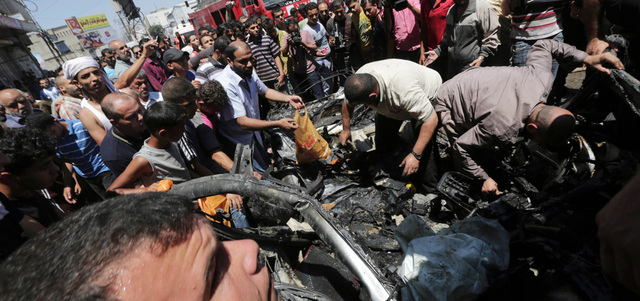 فلسطينيون يجمعون أشلاء الشهداء من بين حطام السيارة التي قصفتها طائرات الاحتلال في غزة. أ.ب