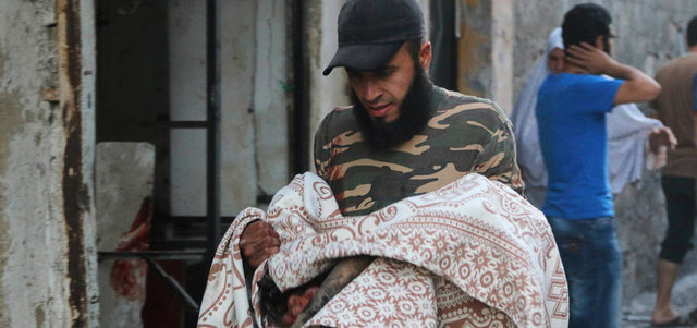 رجل يحمل جثة طفل مغطاة ببطانية قتل في غارة للقوات النظامية على حي قاضي عسكر بحلب.  رويتروز