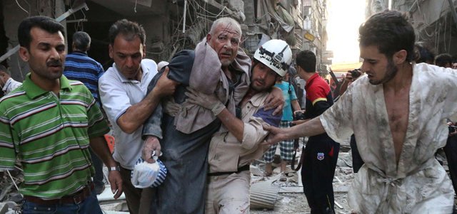 رجال إنقاذ يسعفون رجلاً أصيب بإلقاء القوات النظامية برميلاً متفجراً على حي الشعار بحلب.  أ.ف.ب