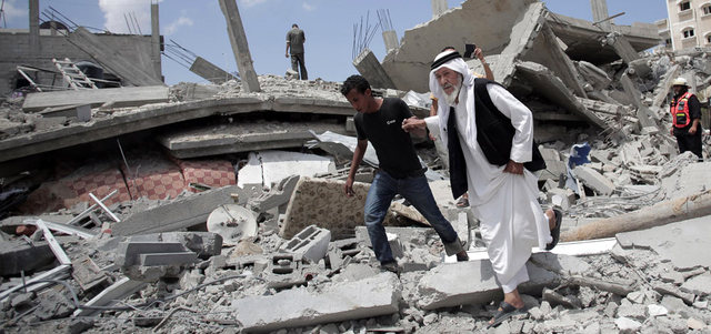 عجوز فلسطيني يسير فوق أنقاض منزل دمّره الاحتلال. أ.ب