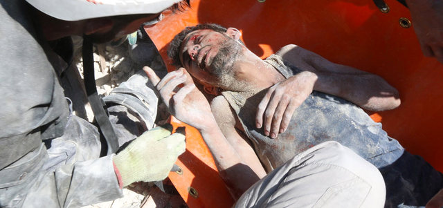 عناصر الدفاع المدني ينقذون رجلاً من تحت أنقاض مبنى تهدم ببرميل متفجر ألقته القوات النظامية على حي باب النيرب بحلب. أ.ف.ب