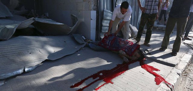 سوري يغطي جثة رجل بعد مقتله ببرميل متفجر ألقته القوات النظامية على حي باب الحديد في حلب.  أ.ف.ب