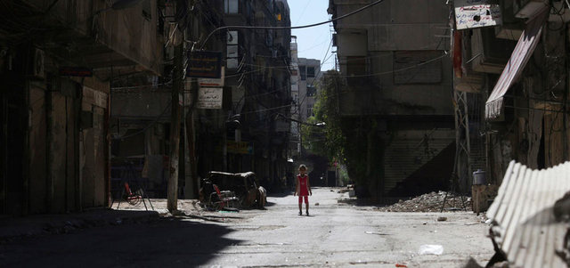فتاة تقف في شارع تضرر بالقصف على بلدة عين ترما بالغوطة الشرقية لدمشق. رويترز