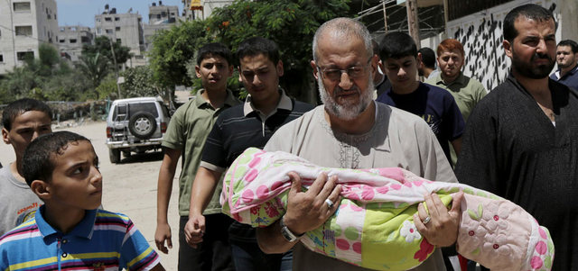 فلسطيني يحمل جثمان طفل استشهد في القصف الإسرائيلي على غزة. أ.ف.ب