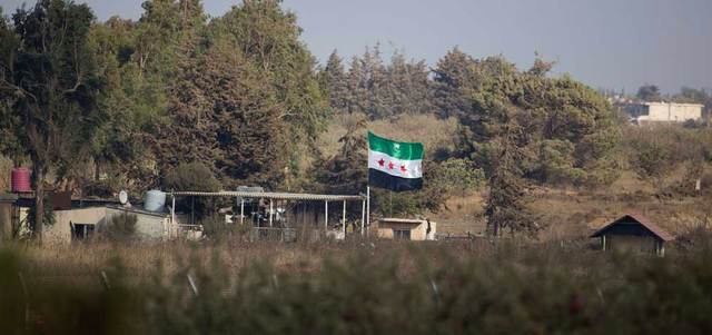 رفع مقاتلو المعارضة «علم الثورة» على الجانب الذي تسيطر عليه سورية لمعبر القنيطرة في هضبة الجولان.  أ.ف.ب