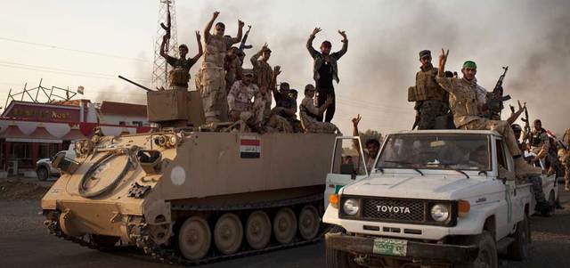 جنود عراقيون يلوّحون لقافلة مساعدات في طريقها إلى قرية آمرلي بعد فك حصارها.  أ.ف.ب
