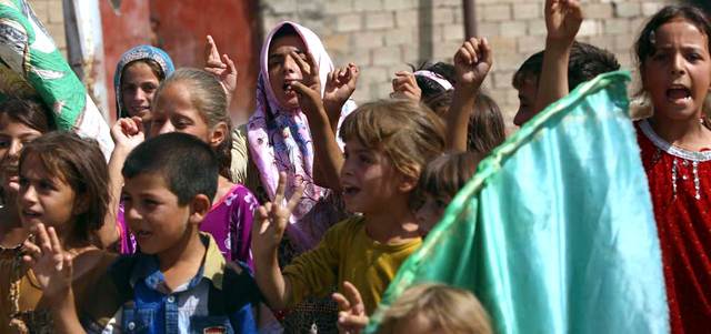 سكان من بلدة آمرلي التركمانية يرفعون شارة النصر ترحيباً بوصول المساعدات بعد فك الحصار عنهم. أ.ف.ب