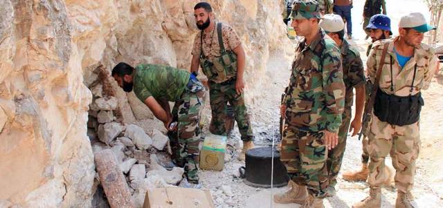 عناصر من القوات النظامية تنظر في كهف كانت تستخدمه المعارضة كقاعدة في ريف حماة.  أ.ف.ب