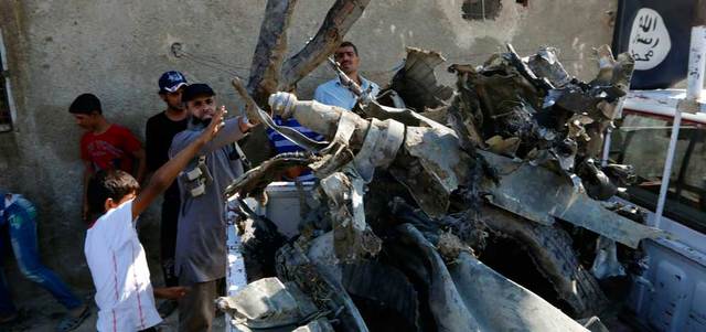 مدنيون يساعدون عناصر من «داعش» على تحميل أجزاء من حطام الطائرة الحربية السورية التي أسقطها التنظيم في الرقة. رويترز