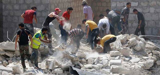 سكان يبحثون عن ناجين تحت أنقاض مبانٍ فجرتها قوات النظام بقنبلة فراغية جنوب إدلب.  رويترز
