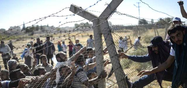 أكراد أتراك وسوريون يحاولون هدم الجدار الحدودي جنوب شرق بلدة سوروس التركية.  أ.ف.ب