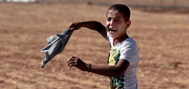 صبي كردي يصرخ في وجه الجنود الأتراك الذين يحاولون إبعاد الأكراد من منطقة الحدود التركية السورية قرب بلدة عين العرب. أ.ف.ب