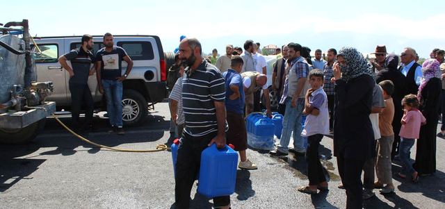 لاجئون سوريون يتجمعون على الطريق المؤدي إلى معبر المصنع على الحدود اللبنانية السورية.  أ.ف.ب