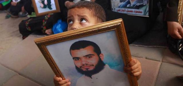 طفل فلسطيني يحمل صورة والده الأسير في سجون الاحتلال خلال تظاهرة دعم للأسرى. الإمارات اليوم