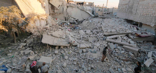 سوريون على أنقاض مبانٍ تهدّمت ببرميل متفجر ألقته القوات النظامية على حي الحيدرية بحلب. رويترز